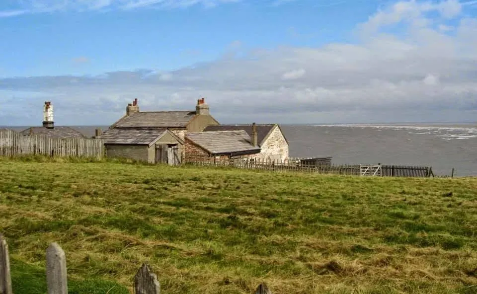 A group of historic island buildings seen across grass