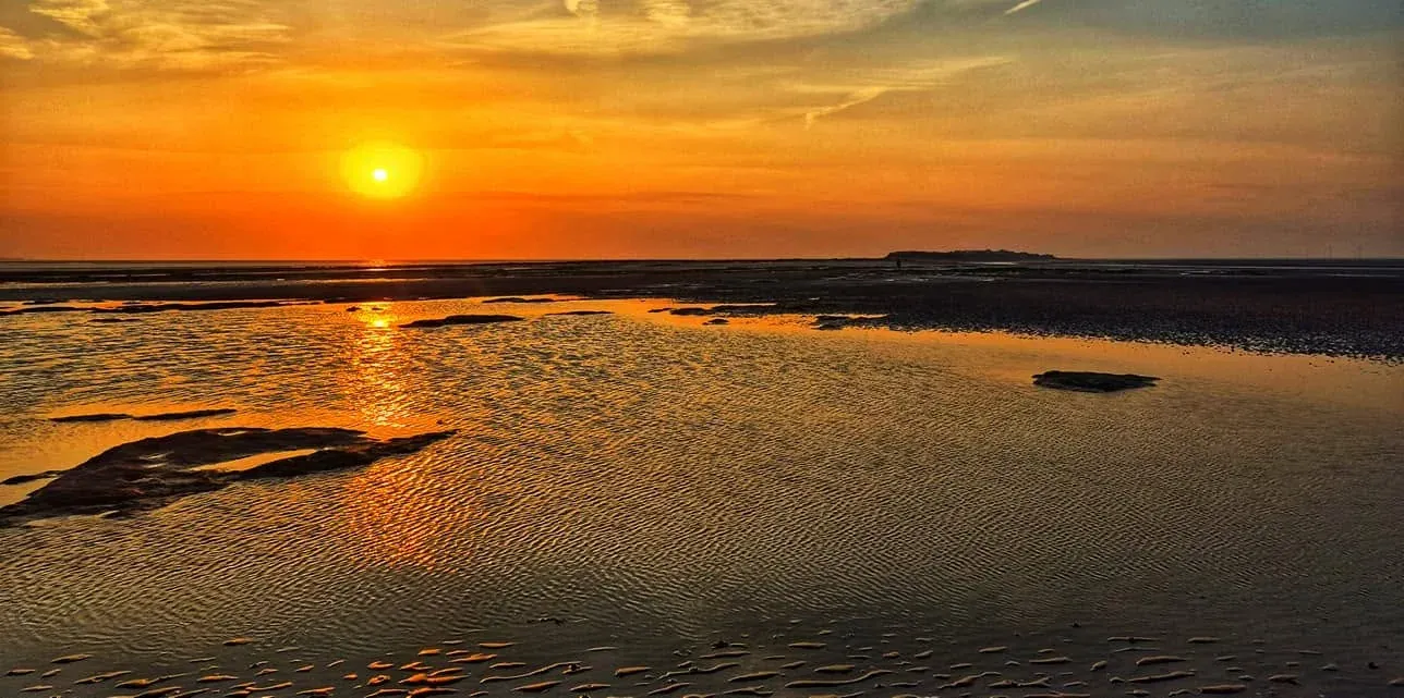 Sunset reflected across pools and rippled sand at low tide