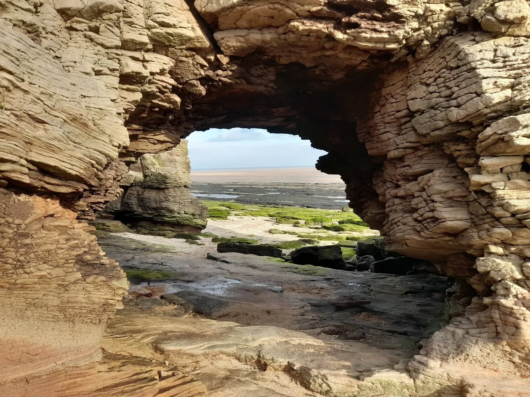 A natural sandstone arch opening onto the shore