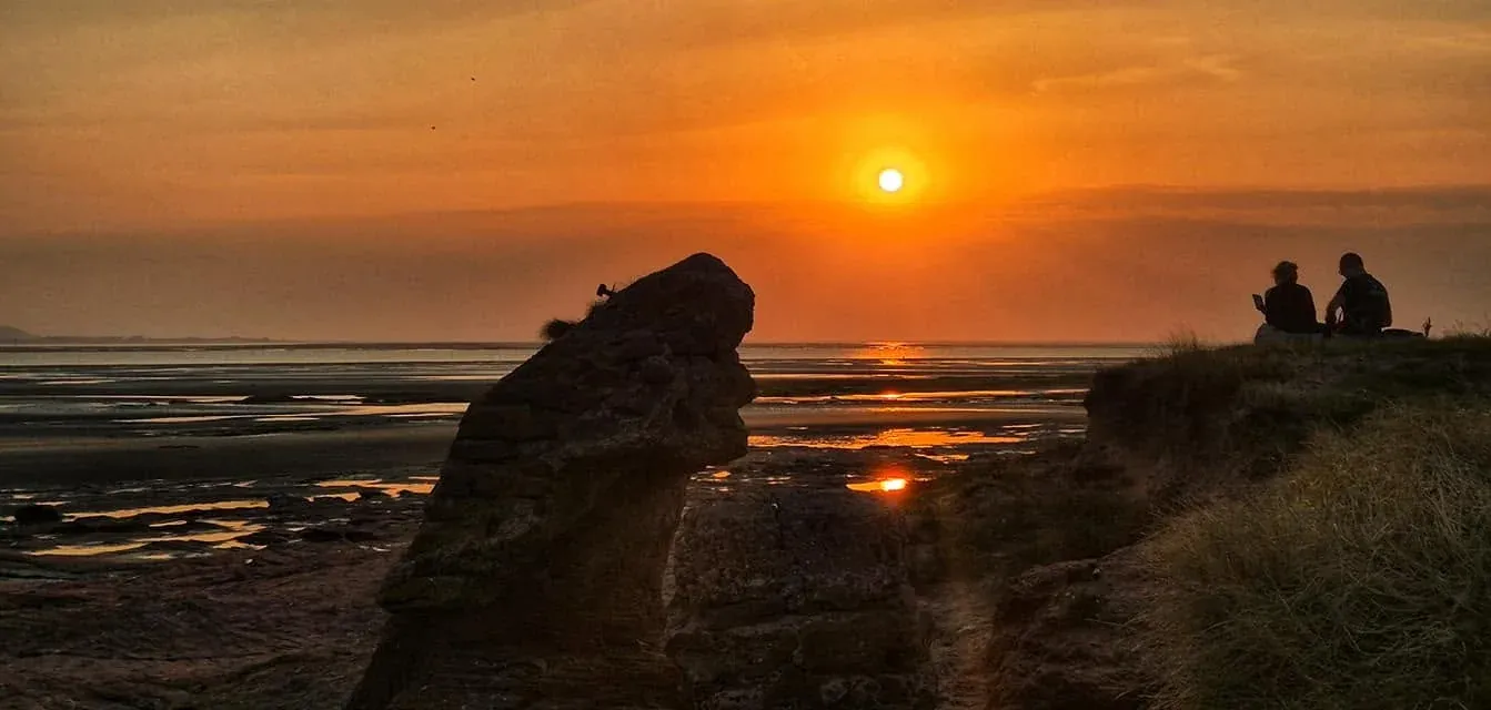 Sunset over the estuary framed by red sandstone rocks